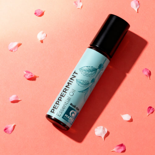 Pure Peppermint Oil Rollerball on a coral backdrop with petals